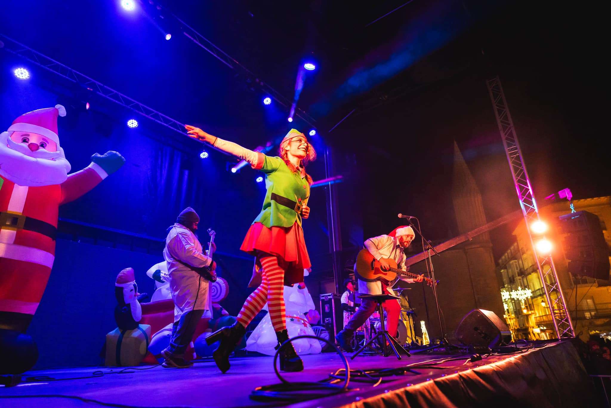 Escenario iluminado con decoración navideña y músico de QuimiRock cantando en directo durante el espectáculo “Mi Plan de Navidad”